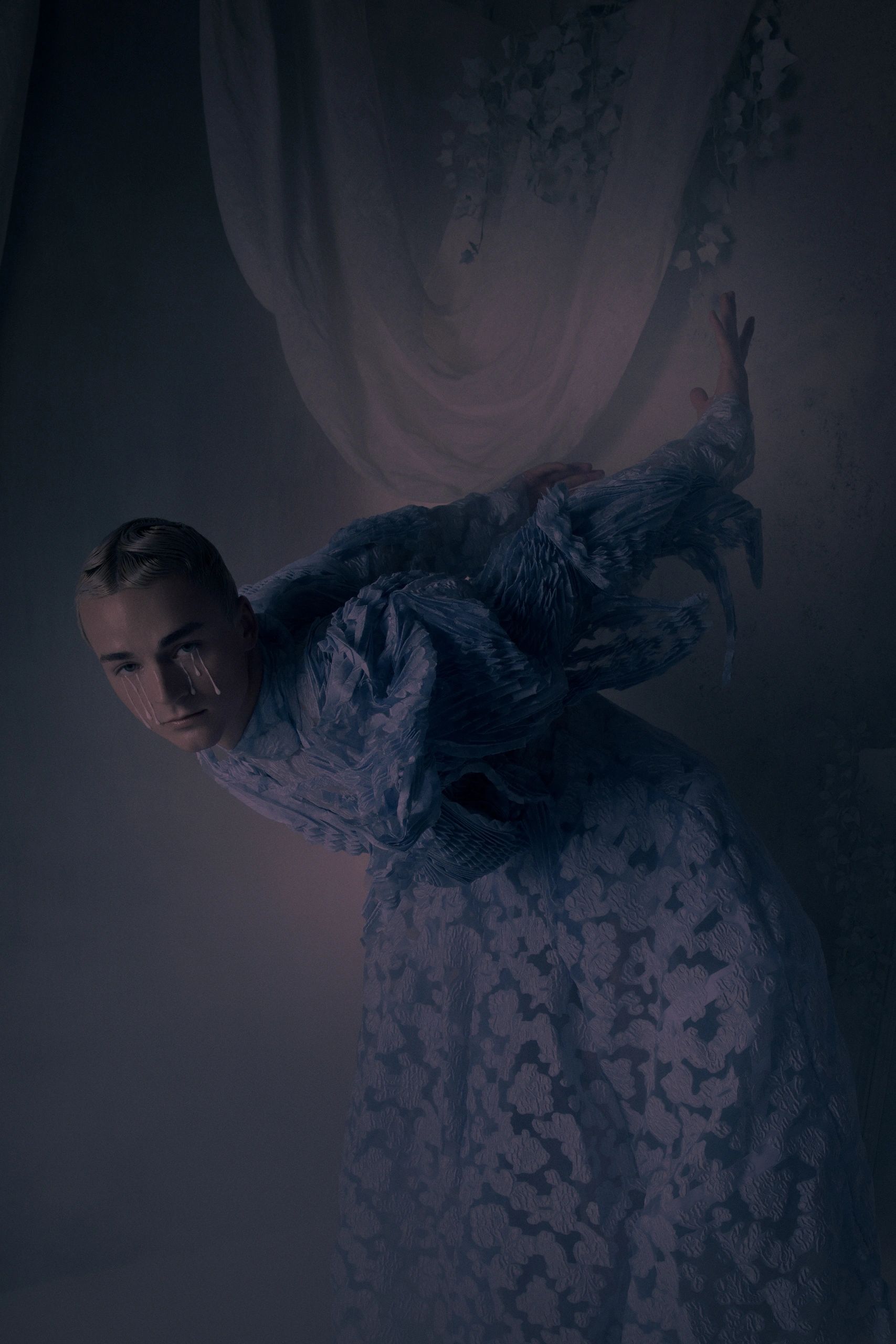 Surreal portrait of a person with tears and textured clothing.