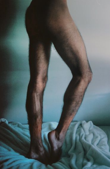 Pernas masculinas peludas em um lençol.
