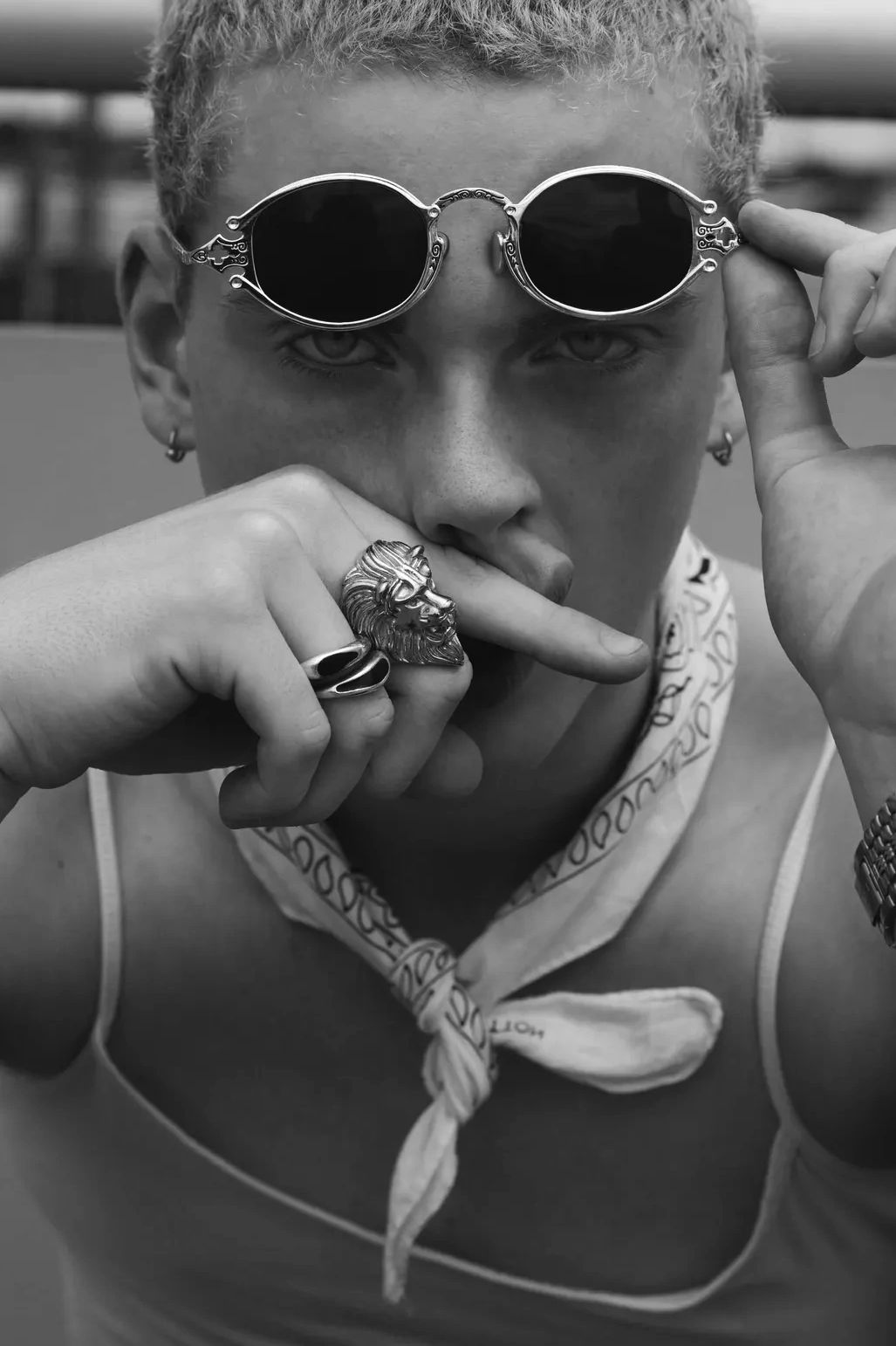 Person with stylish round sunglasses and lion ring.