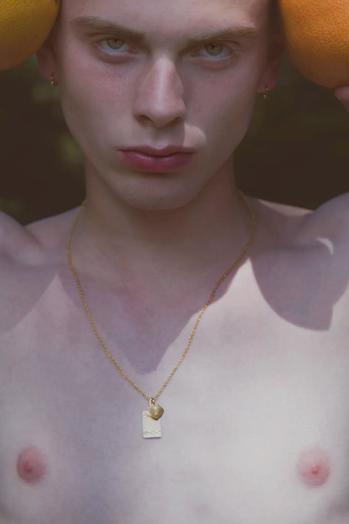 Close-up of a person holding oranges near their face.