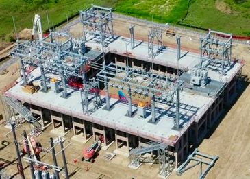 A large electrical substation under construction in a rural area.