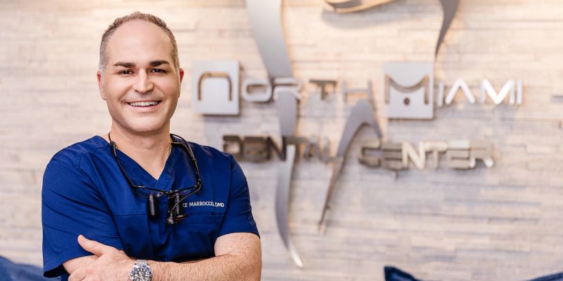 Smiling dentist in blue scrubs at dental center.