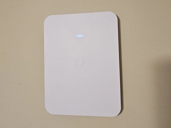 White Ubiquiti network device mounted on a wall.