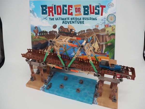 A detailed bridge-building game model with a toy truck and water base.