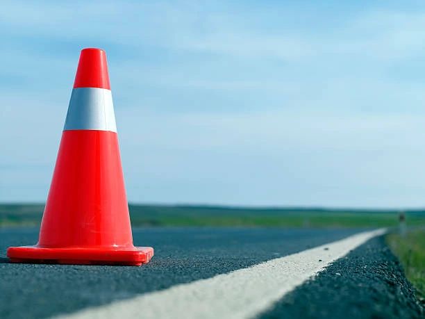 Red traffic cone on the road beside a white line under a clear sky.
