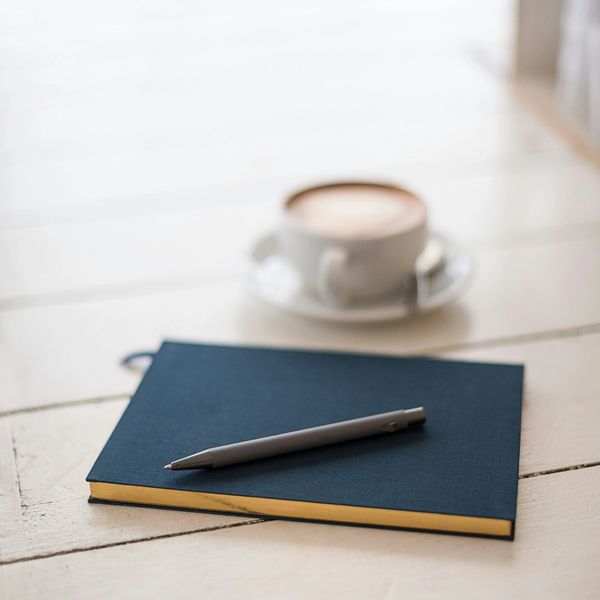 Journal and pen with coffee in the background