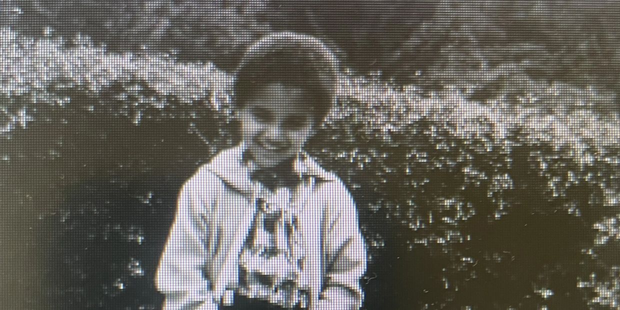 Black and white photo of a smiling child outdoors.