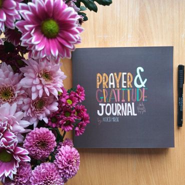 Prayer and Gratitude journal with flowers and pen.
