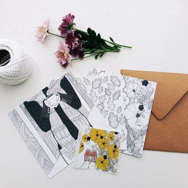 Artistic cards, flowers, and string on a white table.