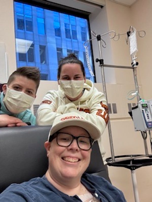 Three people wearing masks in a medical setting, smiling for a selfie.