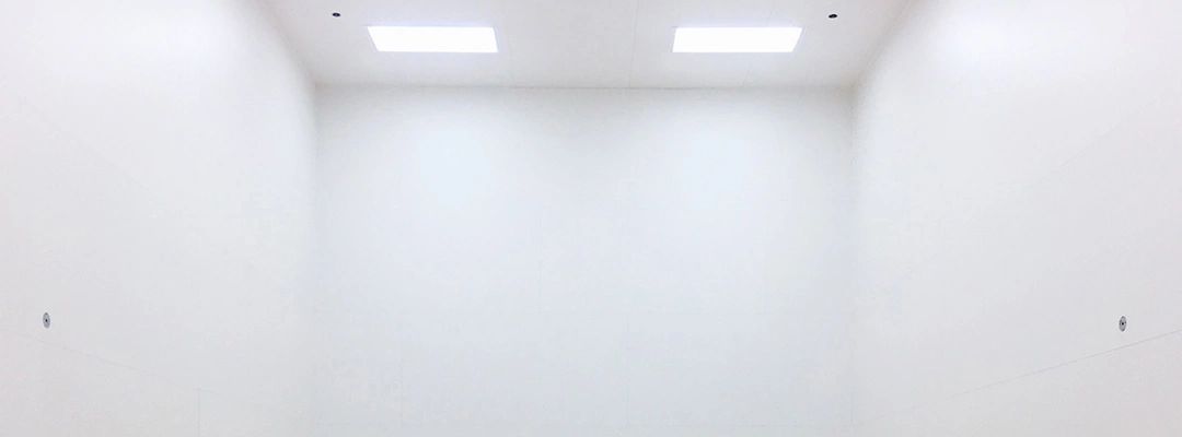 A bright, empty white room with two ceiling lights.