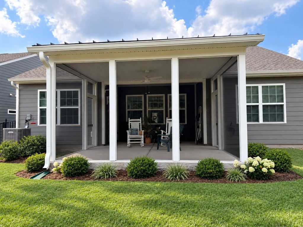 Screened porch with rocking chairs and plants.