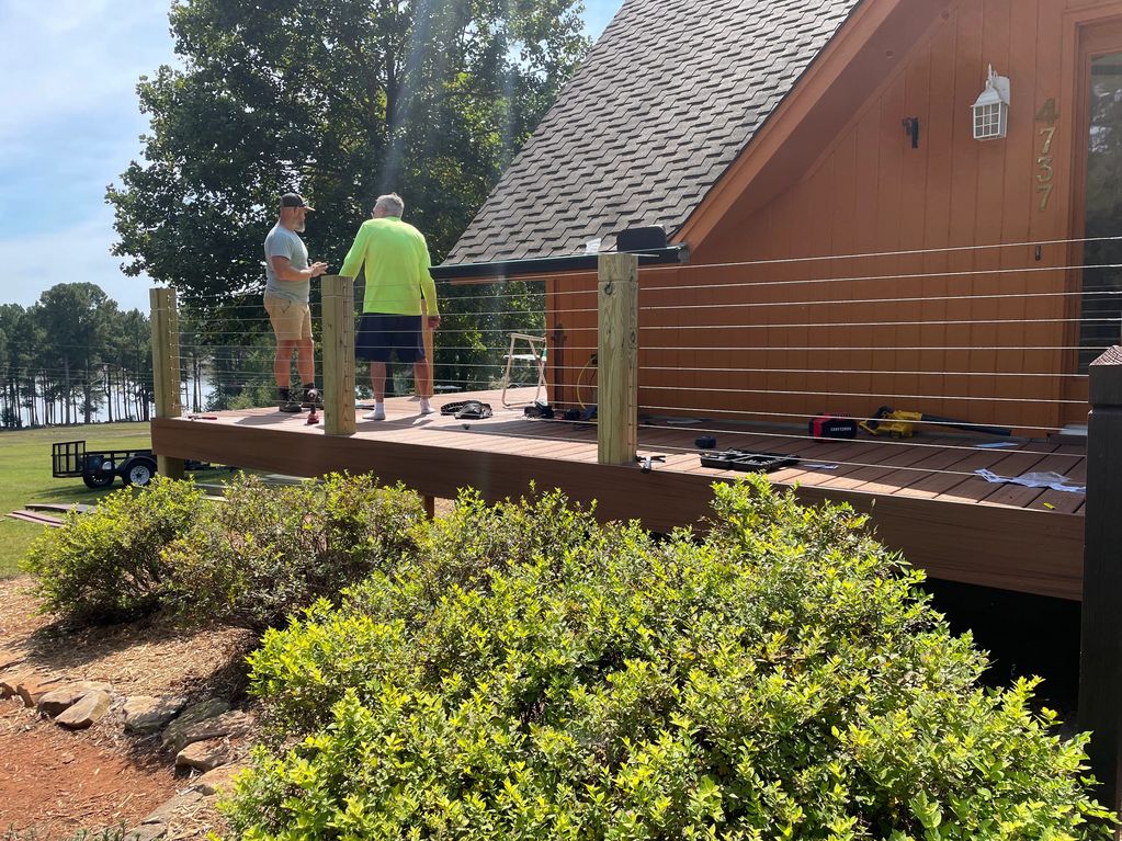 Two men working on a wooden deck near a house.