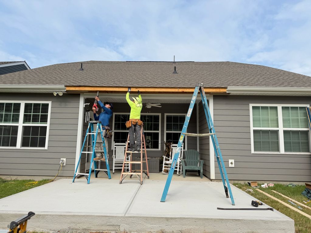 Two workers on ladders fixing the house roof.