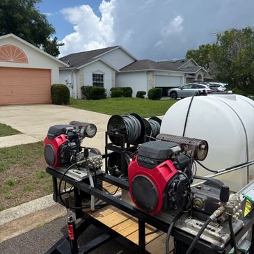 A trailer with two red Honda engines and a large white tank in a suburban neighborhood.