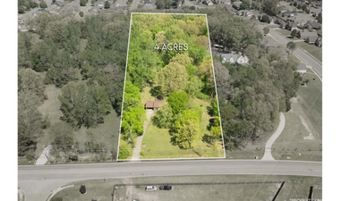 A 4-acre wooded plot with a house, bordered by a road and nearby residential area.