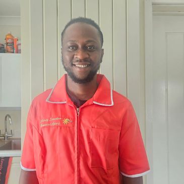 Man in a red uniform smiling indoors.
