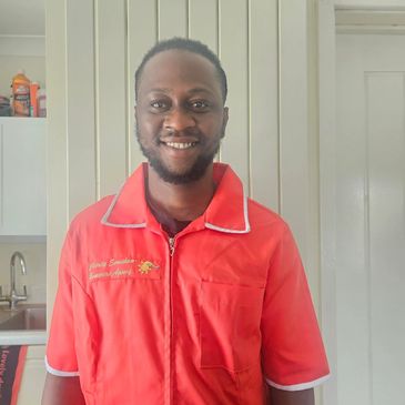 Man in a red uniform smiling indoors.