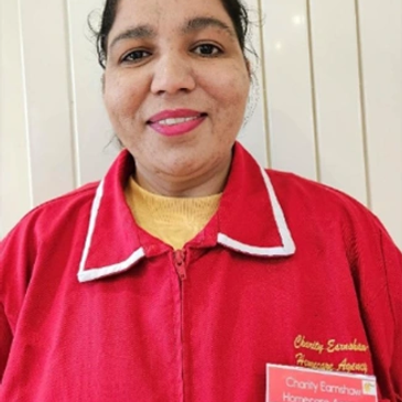 A smiling woman in a red uniform with a homecare agency badge.