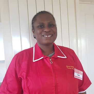 Woman smiling in a red uniform with a name tag.
