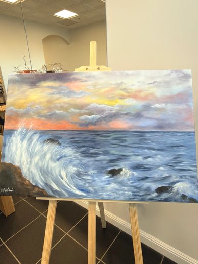 A painting of an ocean wave crashing against rocks at sunset.