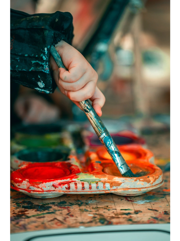 A baby hold the brush with painting and colour