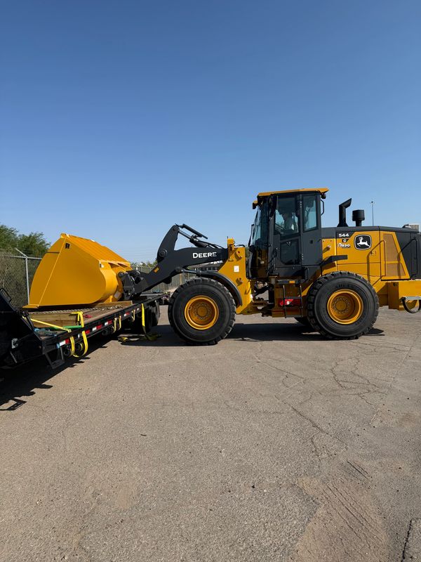 Yellow John Deere construction loader on flatbed trailer.