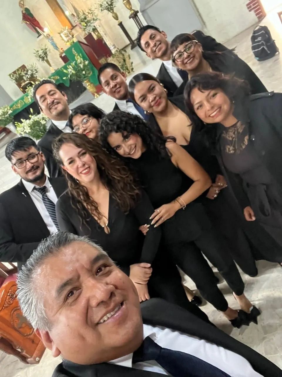 A group of smiling people dressed formally inside a church.
