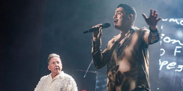 Two male singers performing on stage with intense expressions.
