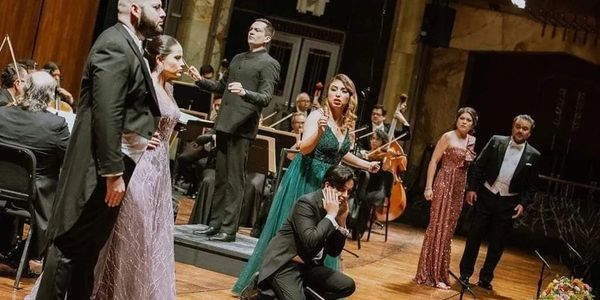 Opera singers performing passionately on stage with orchestra.