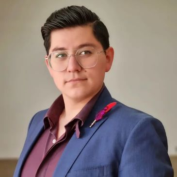 Young man in glasses wearing a blue suit with a red shirt and boutonniere.