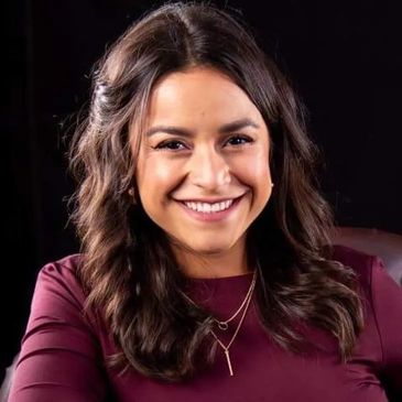 Smiling woman with wavy dark hair in a burgundy top.