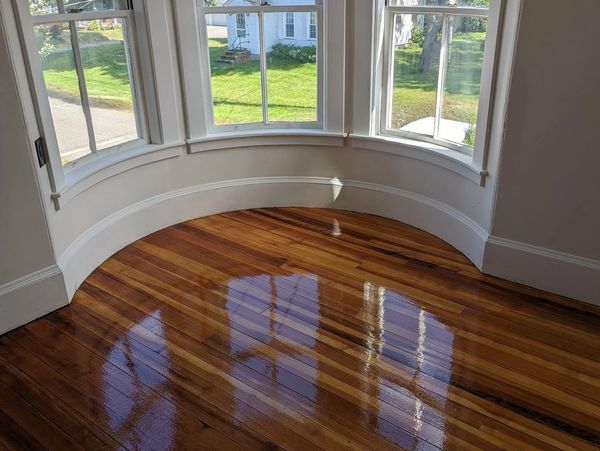 Bright room with shiny wooden floor and curved bay windows.