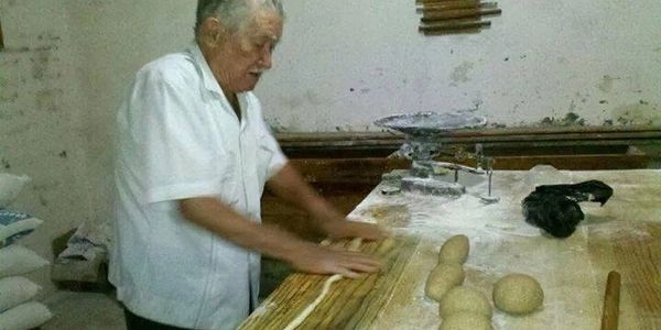 Man making dough in a rustic kitchen.