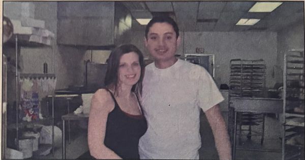 A smiling couple posing in a commercial kitchen.