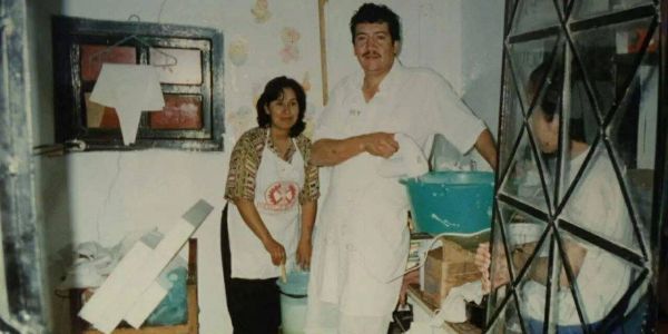 Two people in aprons cooking or baking indoors.