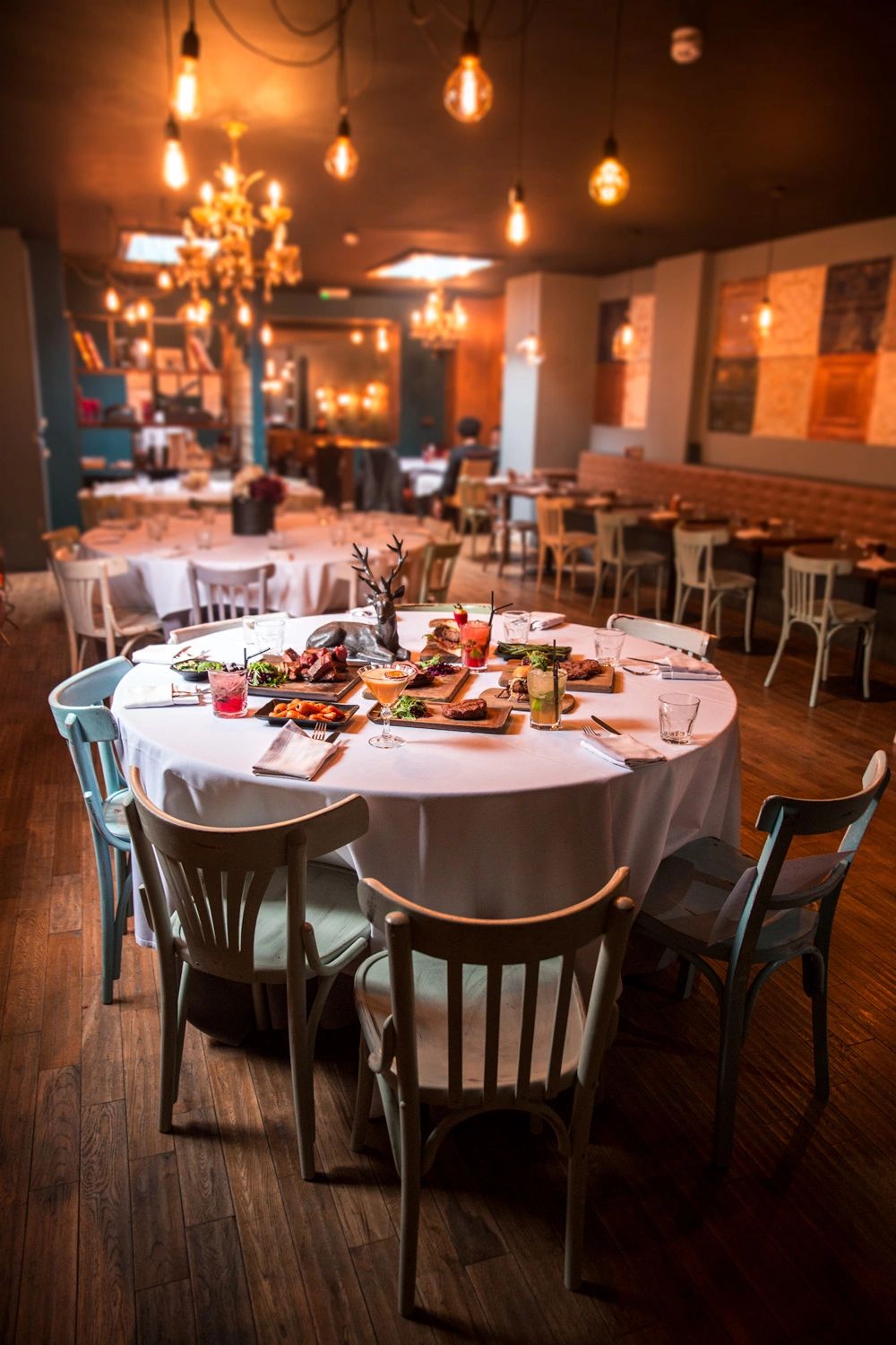 A warmly lit dining table with food and drinks in a cozy restaurant.