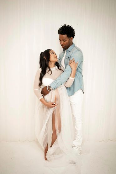 Expectant couple sharing a loving moment in soft, elegant attire.
