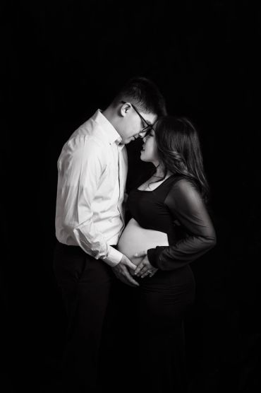 Expectant couple tenderly embracing, highlighting the pregnancy.