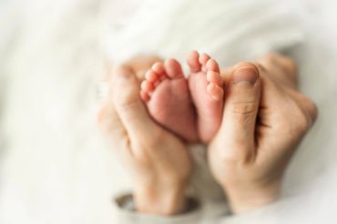 Adult hands gently holding tiny baby feet.