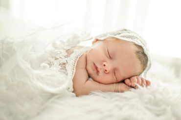 Sleeping newborn baby wrapped in a soft white blanket.