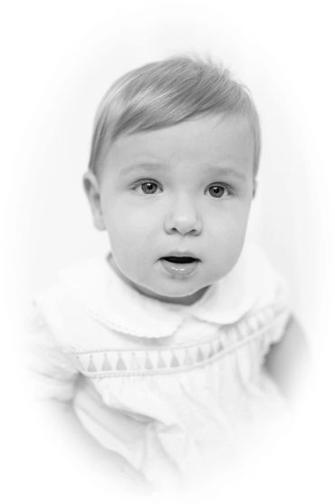Black and white portrait of a curious baby with light hair and big eyes.