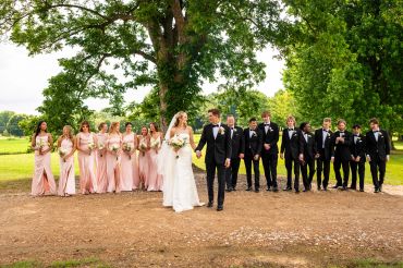 Wedding party with bride, groom, bridesmaids, and groomsmen outdoors.