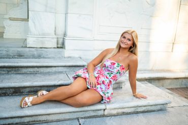 Young woman in a floral dress relaxing on stone steps outdoors.