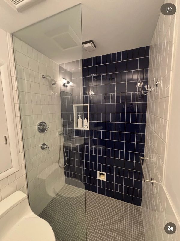 Modern bathroom with contrasting white and dark blue tiles and a glass shower enclosure.