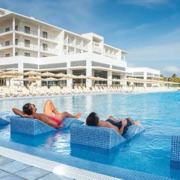 Two women relaxing on chairs in a pool at a resort.