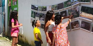 Children observing photos displayed on an outdoor wall.