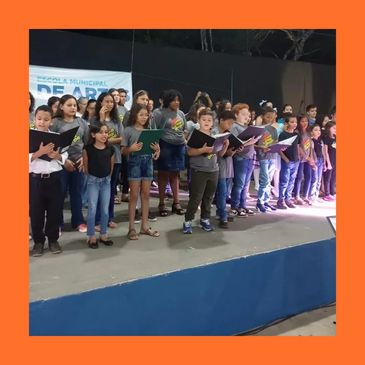 Children singing together on stage during a community event.