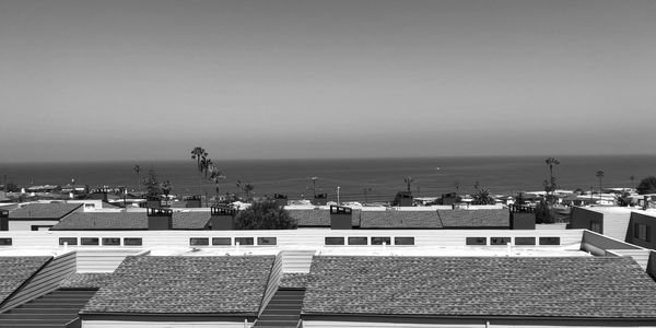 Clear ocean view above rooftops and palm trees.