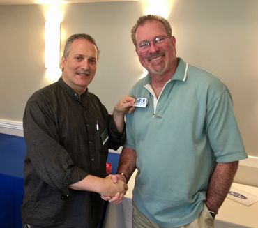 Photo of Dan R presenting Rich B with silver badge
